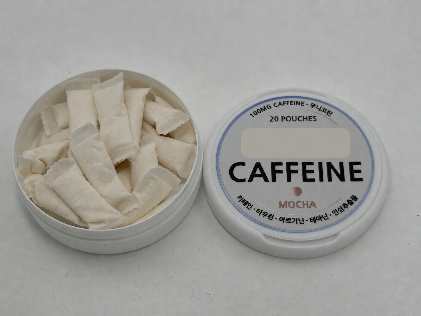 An open caffeine pouch can and an anonymized caffeine pouch lid.